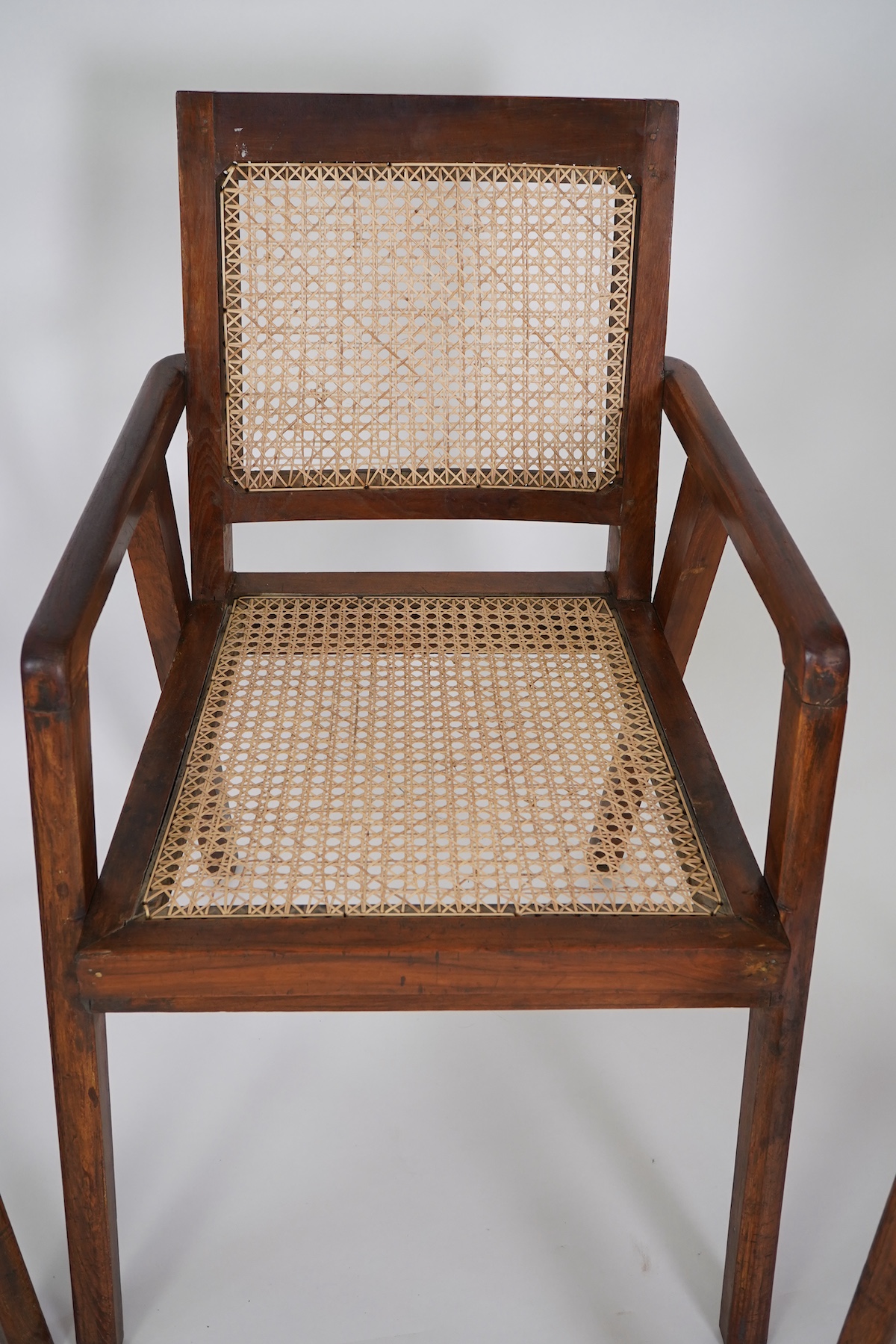 Manner of Pierre Jeanneret (Swiss, 1896-1967): A set of four solid teak and braided canework armchairs